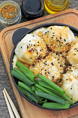 Chinese dumplings with soy sauce in a cast iron skillet. Spices, chopsticks.