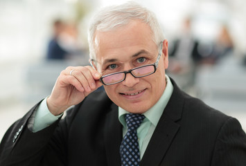 closeup of a senior businessman adjusting his glasses