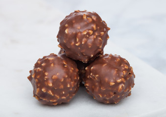 Luxury chocolate candies with hazelnuts on marble board and white background.
