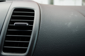 close up to an air conditioner fan inside a modern car, black leather board of a modern car