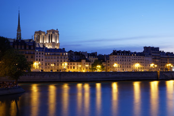 Naklejka na ściany i meble Paris, France - July 5, 2018: Notre Dame Cathedral with Paris cityscape and River Seine at dusk, France