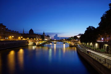 Paris, France - July 5, 2018: Conciergerie  with Paris cityscape and River Seine at dusk, France