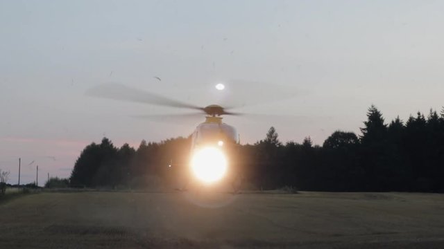 German rescue helicopter taking off in field in twilight with lights on