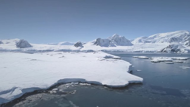 Aerial Flight Over Antarctica Shoreline, Ocean And Snow Covered Land. Drone Overview Shot Of Antarctic Continent. White Winter Landscape. Mighty Polar Mountains Background. 4k Footage.