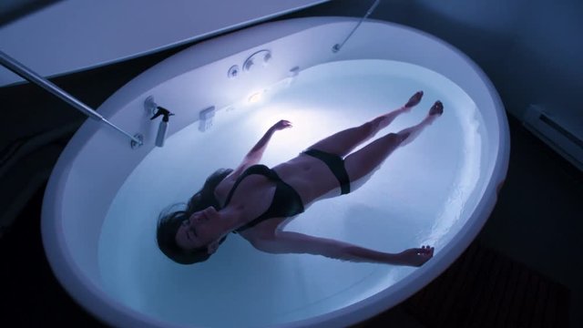 Young Woman in float tank, sensory depravation tank at spa