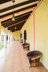 hallway inside a rustic hotel, group of three armchairs made of wood, wooden bars on the roof of a hallway in a hotel