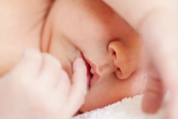 Little newborn baby boy sleeping in white blanket, lying on bed.