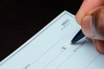 writing a check with blue pen on dark table