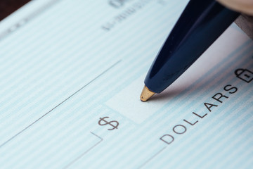 writing a check with blue pen on dark table