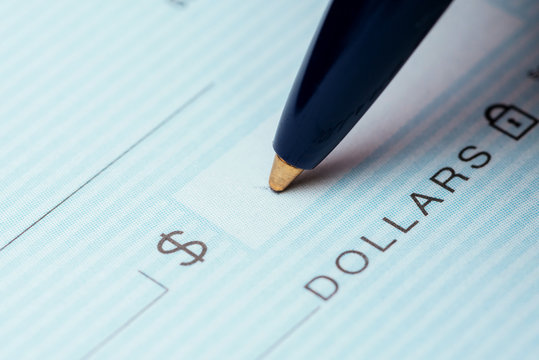 writing a check with blue pen on dark table