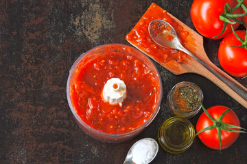 Cooking homemade tomato sauce. Tomato sauce in a bowl of a blender. Tomatoes and spices. Recipe for tomato sauce.