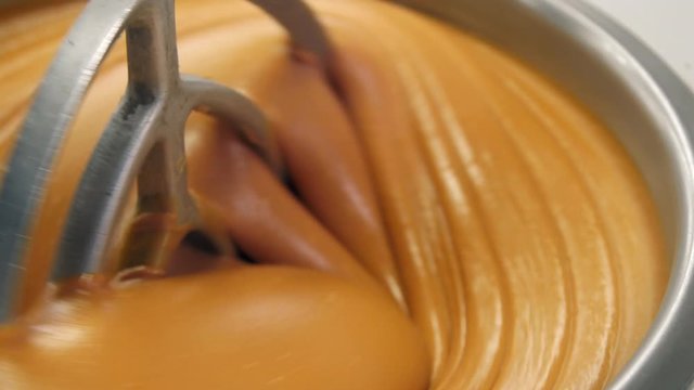 Close up shot of delicious peanut butter mixing in large bowl