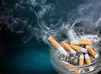 Burning cigarettes in ashtray on white background