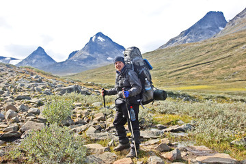 Man traveler with a backpack on a tourist route in the highlands