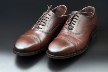 Classic men's brown Oxford shoes on dark background
