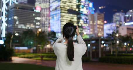 Woman take photo on cellphone in Hong Kong at night