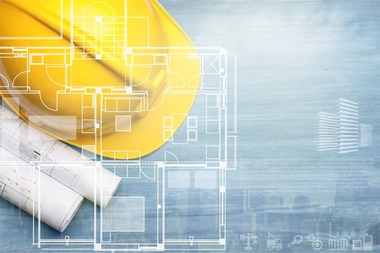 Yellow helmet with blueprint on wooden background