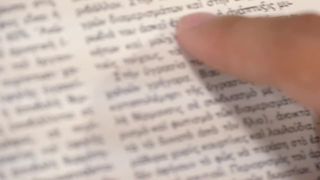 Macro close-up of a person tracing the words in a book with their finger as they read