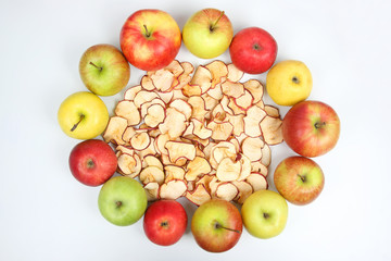 Dried Apple slices surrounded by fresh apples on white background