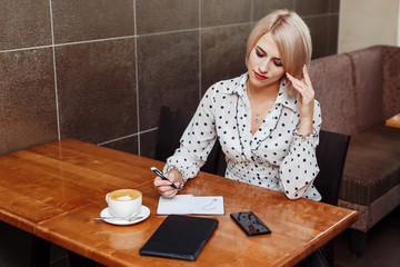 Fototapeta premium Woman in cafe sitting and writing in notebook