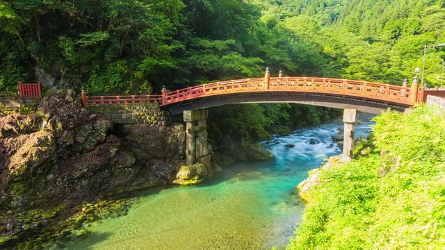 Water and dawn mist flowing underneath the colorful Unesco World Heritage, Sacred Shinkyo Bridge above the Daiya River on an early morning in Nikko, Japan. Zoom out 4k time-lapse at 30fps