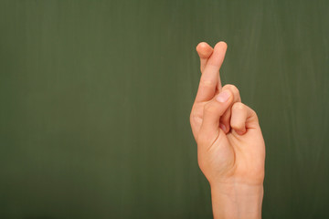 Crossing fingers sign in front of a chalkboard