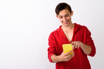 Studio shot of happy young handsome man smiling while using mobi