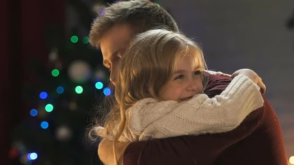 Loving father admiring little daughter tightly hugging her, twinkling of lights