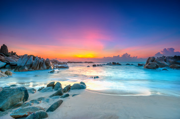 Beautiful sunrise on the beach as the sun rays in the sky purple and below the waves lapping at the shore of the soft great to welcome the new day