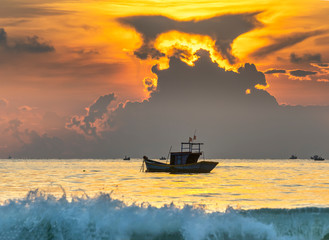 Beautiful beach scene in the morning as the sun rises beside the fishing boat of fishermen as welcoming new interesting day.