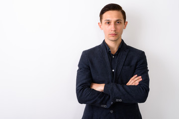 Studio shot of young handsome businessman with arms crossed agai
