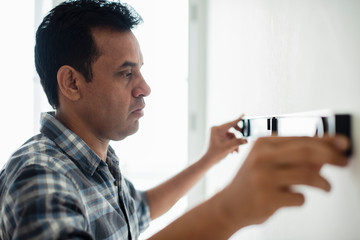 Man using a spirit level on a wall - Powered by Adobe