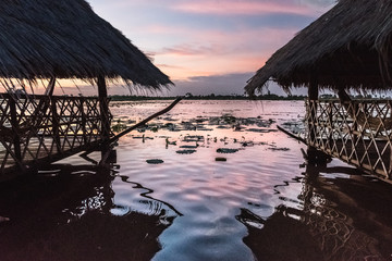 magical sunset with reflections in the lake with traditional straw huts