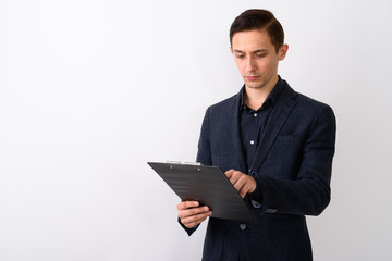 Studio shot of young handsome businessman reading on clipboard a