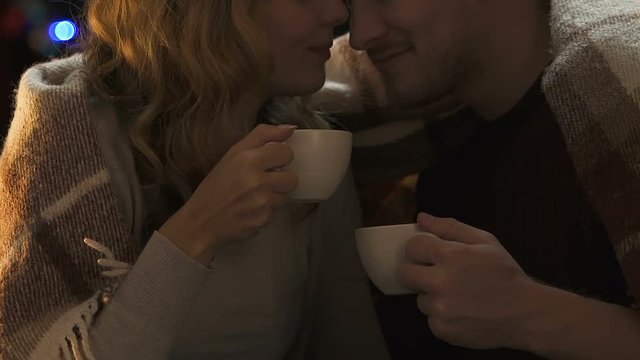 Happy lovers drinking coffee at New Year eve, warming and caressing each other