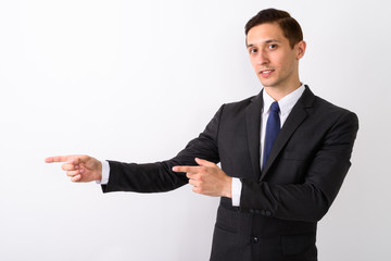 Studio shot of young handsome businessman showing something whil