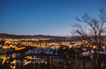 Blurred background of Granada city in the evening with twilight sky.
