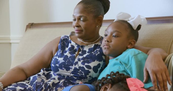 Scene pans up from a cute little African American girl who is about to doze off while her aunt and big sister watch TV.