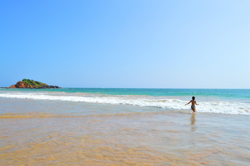 Fototapeta na wymiar happy girl enjoys the waves of the Indian ocean on the island of Ceylon