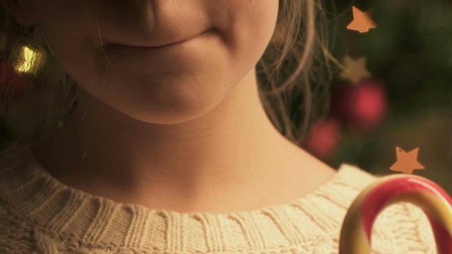 Little girl licking candy cane, delighted with delicious Christmas dessert