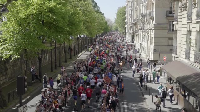 Marathon runners running in Paris, shot from a bridge. Slow motion.