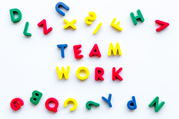 Teamwork training concept. Text teamwork lined with colored letters near toy letters on white background top view space for text