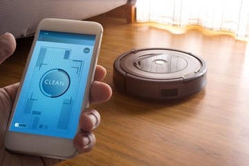 Hand holding smartphone with application control robot vacuum cleaner on screen mobile phone.Smart...