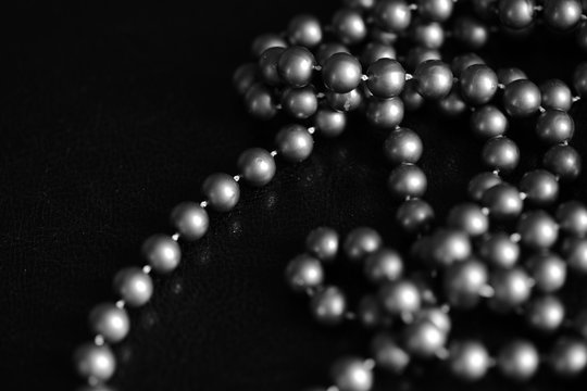 Long necklace of large beads on a dark background close up. Black and white