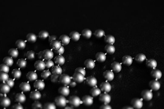 Long necklace of large beads on a dark background close up. Black and white
