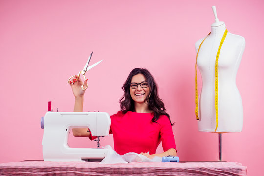 sewing pattern,sewing machine and maniken in studio pink background.seamstress curve template. tailor creates a collection outfits sews clothes in workshop. young woman designer clothes notes ideas