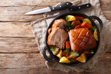 Tasty crispy pork baked in beer with vegetables and gravy close-up in a frying pan. horizontal top...
