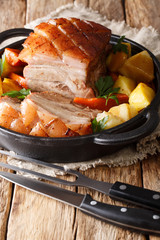 Traditional German Dishes: Krustenbraten pork slow baked in the beer with  vegetables closeup on the pot. vertical