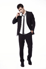 A young guy in a black suit with a coffee Cup on a white background. Advertising, creativity. Coffee to go.