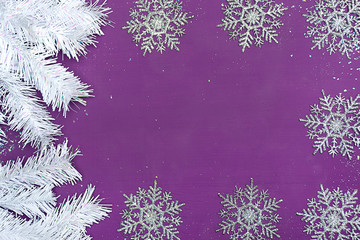 Christmas background with free space. Textural wooden background of bright purple color with white artificial fir branches, artificial snow, sparkles, Christmas balls
